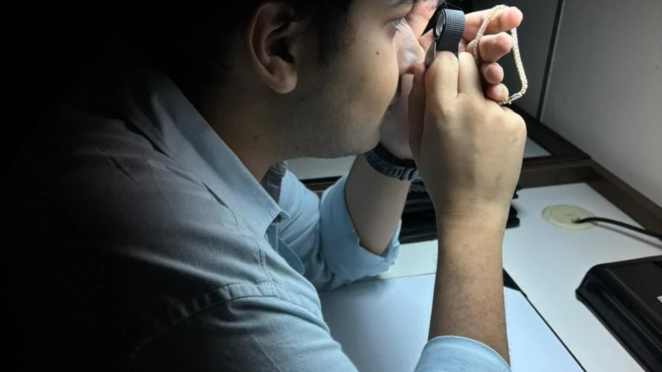 A jeweller inspecting a piece of jewellery through a loupe