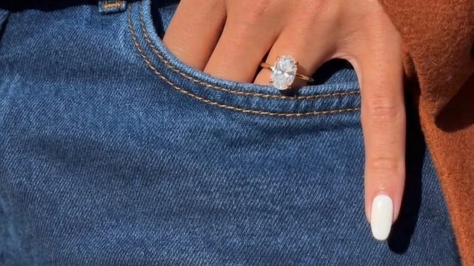 An oval diamond ring worn on a hand, showing its real-world scale